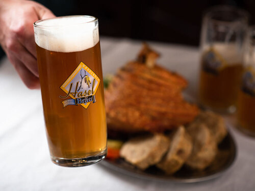 Haselbräu Bier mit knuspriger Stelze im Hintergrund